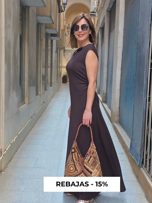 imagen de modelo con vestiido y bolso en color chocolate en un callejon de lujo